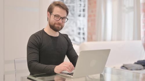Bearded Man Working At Laptop Gives Thumbs Up