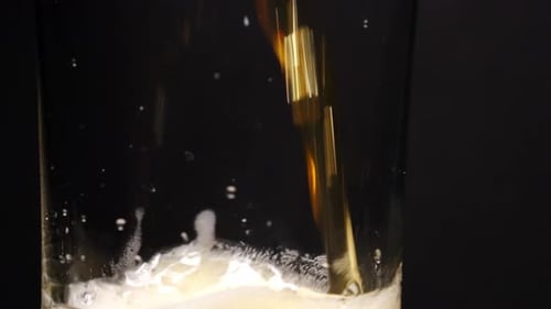 Slow Motion of Beer Pouring Into Glass with Swirling Foam