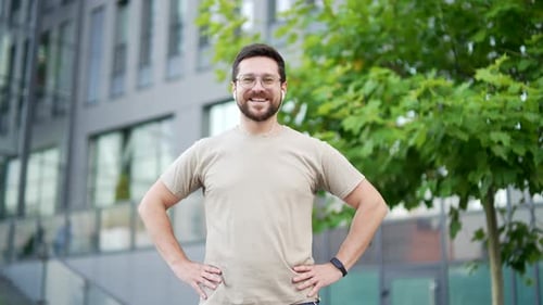 Portrait of happy adult sporty man in t-shirt looking at camera standing on city street. Smiling