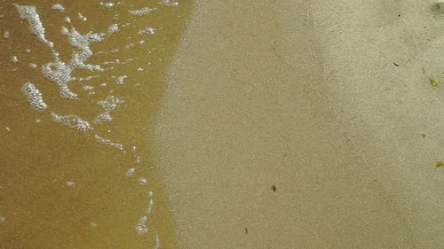 Slow motion, View of the sea shore, Foam from water poured into the sand, sand and water on the coas
