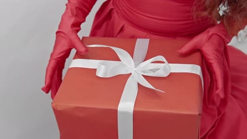 Woman unties a white bow on an orange gift