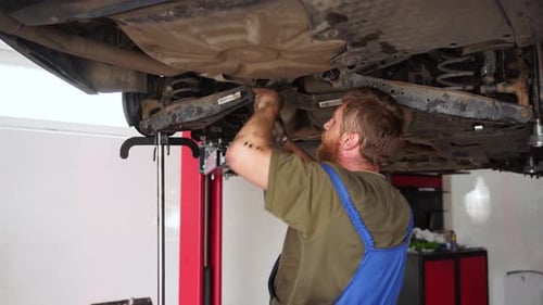 Mecânico de automóveis conserta suspensões de veículos. Especialista examina e ajusta as condutas do material rodante do carro