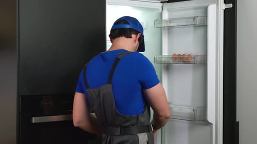 Repairman Fixing Modern Refrigerator in Home