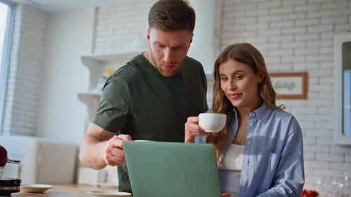 Couple Using Laptop in Modern Kitchen at Home