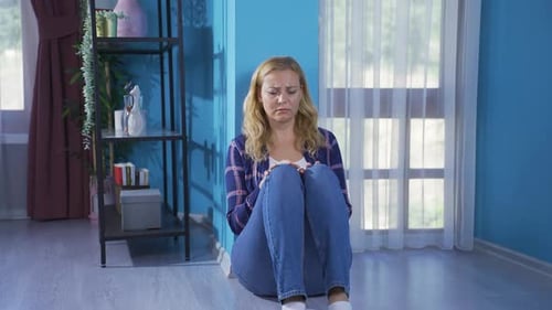 Distressed Woman Sitting on the Floor in Home
