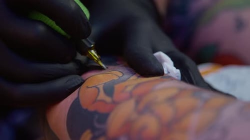 Hands of Tattooist Drawing on Skin Using Tattoo Machine