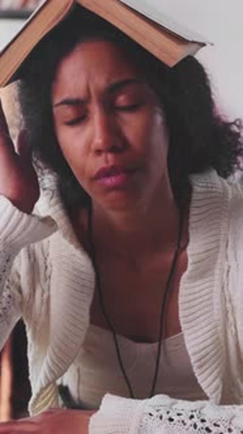 Young Funny African American Business Woman Fooling with Book Sits at Workplace