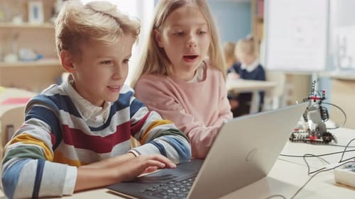 Children collaborating with computer and robotics in classroom