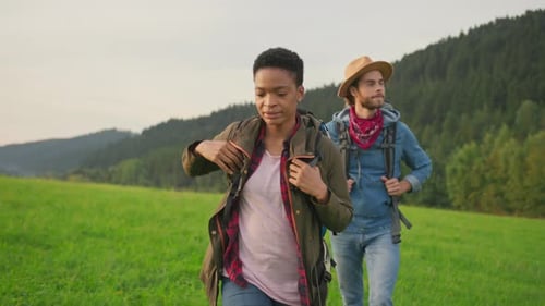 Couple Hiking Through Green Field in the Countryside