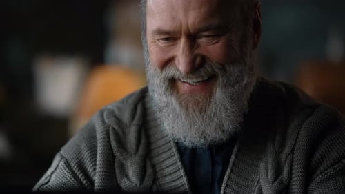 Senior Man Smiling Happily While Using Computer Indoors