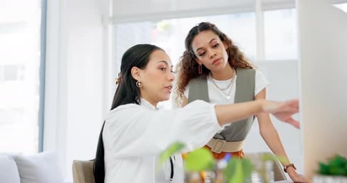 Two Women Discussing Work on Computer in Office