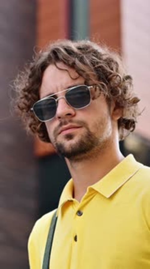 Stylish Man with Curls Poses in Sunglasses