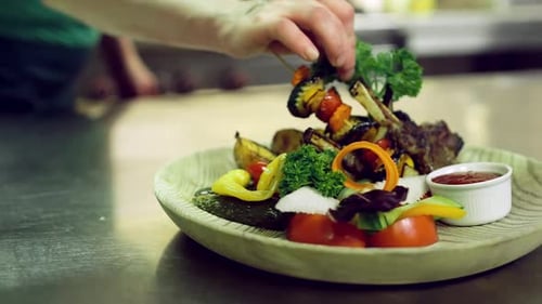 Chef Garnishing Plate of Grilled Meat and Vegetables