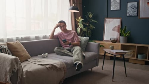 Relaxed man using phone on sofa at home