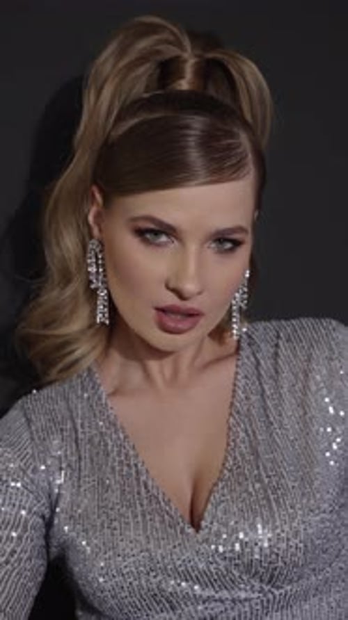 Glamorous Blonde Woman Behind Shimmering Silver Curtain