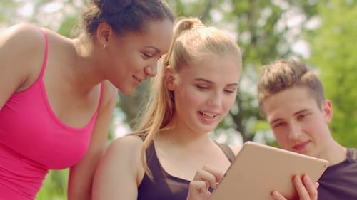 Smiling Friends Using Tablet in a Green Park
