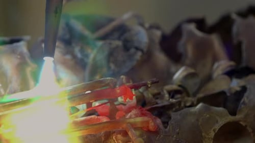 A blacksmith uses gas welding (oxyacetylene) to melt a brass saxophone, resulting in destructive spa