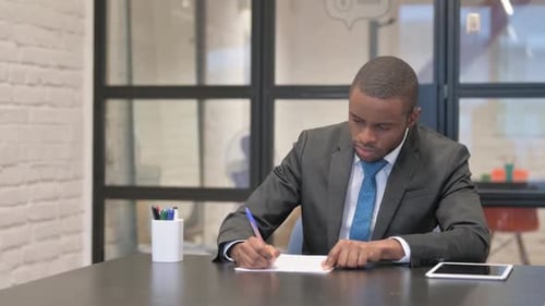 African Businessman Writing a Letter in Office