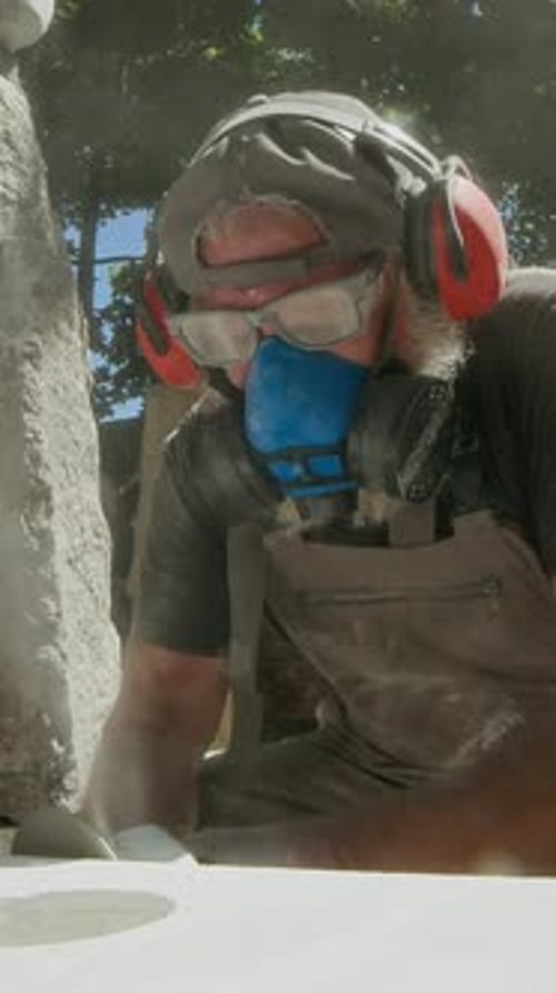 Vertical of Craftsperson Working with Angle Grinder on Stoneware Outdoors