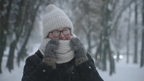 Porträt einer Frau, die sich in einen Schal wickelt und sich im Schneesturm mit ihrem Atem wärmt