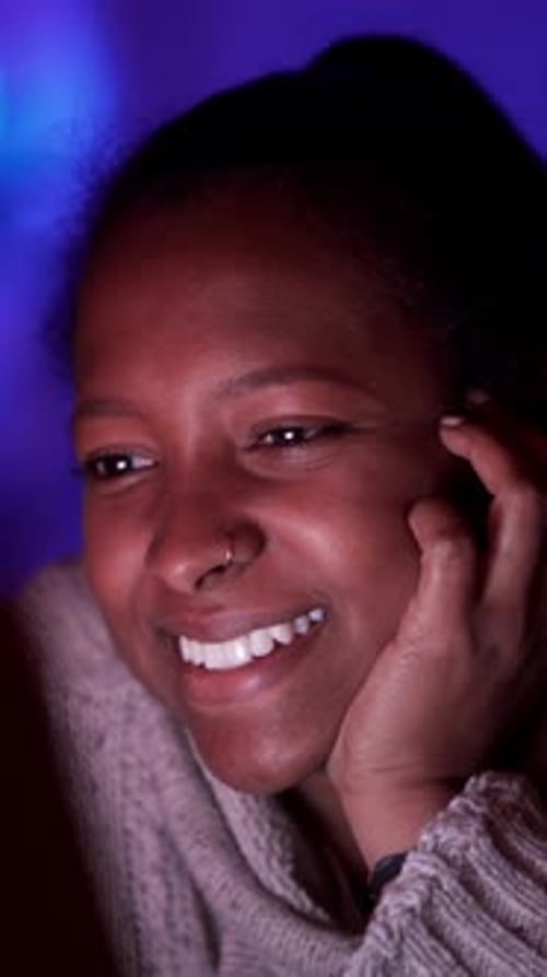 Jeune fille afro-américaine souriante regardant un ordinateur portable penchée sur la main dans une femme latine foncée allongée