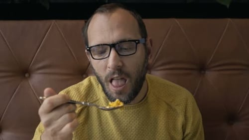 Handsome young man enjoys a delicious healthy salad lunch at a bright cafe