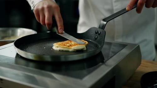 Person Cooking Pancake in Pan with Spatula