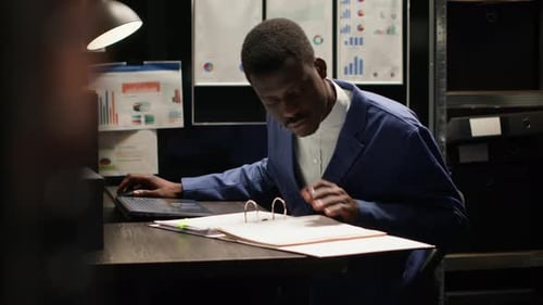 Man Analyzing Data on Laptop in Dark Office