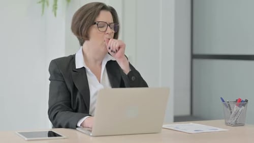 Senior Woman Coughing While Working at Laptop