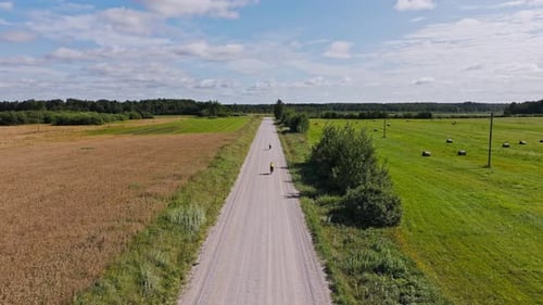 Two Cyclists Ride Rural Gravel Road - Adventure Through Northern European Fields