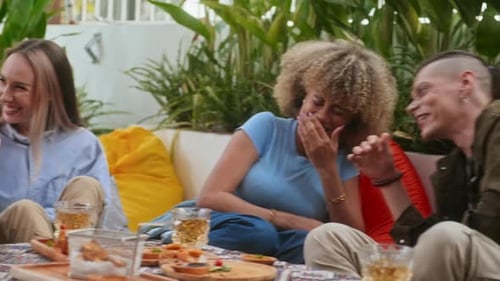 Friends Laughing at Jokes while Hanging Out Together in Outdoor Cafe