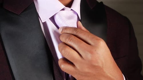 Man in Burgundy Tuxedo adjusts Tie