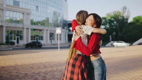 Two Young Women Meet in the Park Girlfriends Met in the Park The Girls are Happy to See Each Other