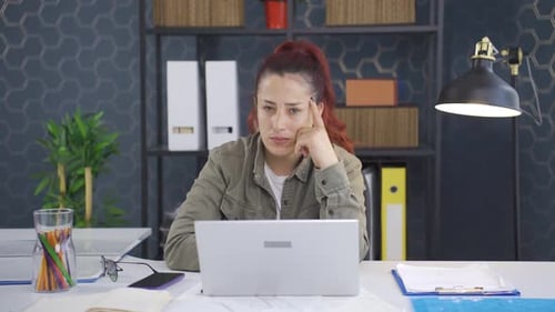 Woman Thinking at Her Desk in Office