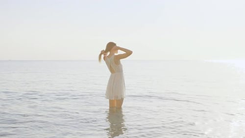 Young Woman Standing in Ocean Water at Beach