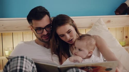 Loving Family Reading Storybook in Bed Together
