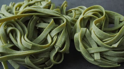 Fresh homemade green pasta tagliatelle. Raw homemade spinach pasta. Fettuccine pasta raw. Nest of gr