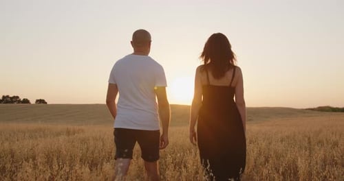 Un couple amoureux se promène dans le champ, se tenant la main.