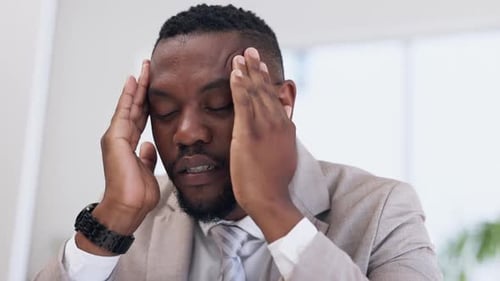 Stressed Businessman Rubbing Temples in Office