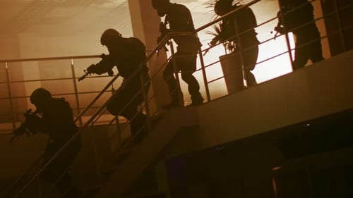 Eine maskierte Gruppe bewaffneter SWAT-Polizeibeamter rennt aus einem zweiten Stock in einem dunklen Büro die Treppe hinunter