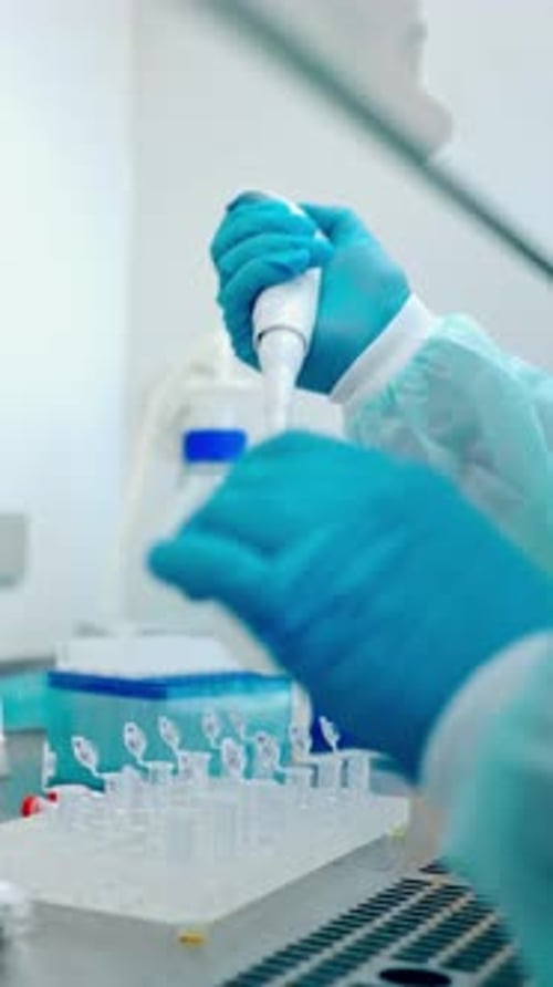 Hands Pipetting Liquid into Vials in Laboratory