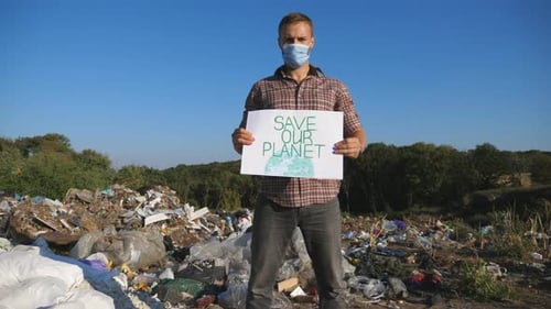 Adult Holding Save Our Planet Sign in Landfill