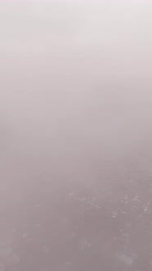 Vertical Drone Flight Through Clouds Revealing a Big City with Red-Roofed Houses Below