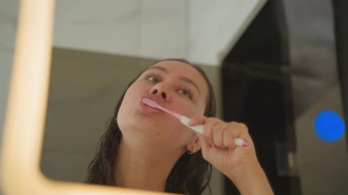 Hotel Mirror Woman Brushing Teeth with Playful Expressions LED Frame Glow Cheeky Nighttime Mood in