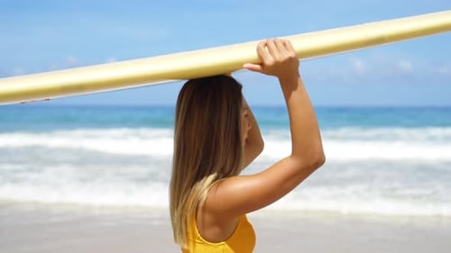 4K Asian woman holding surfboard walking to the ocean in summer sunny day.