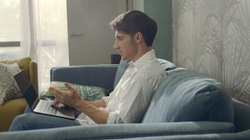 Young Man Using Laptop Computer on Sofa at Home
