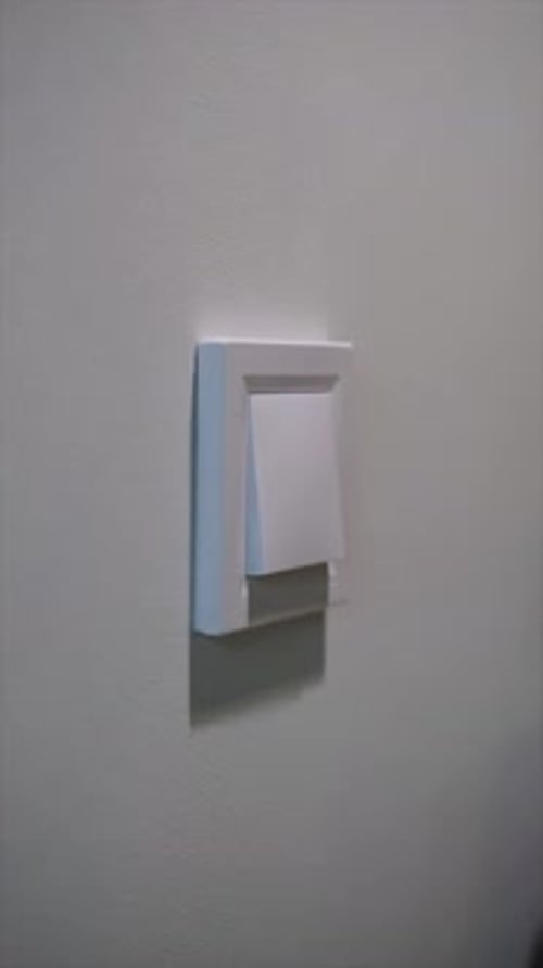 Uma mão feminina acende e apaga a luz pressionando o botão do interruptor na sala. Luzes acesas