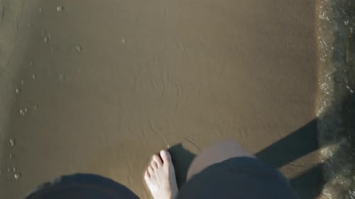 Top view of female legs with shorts walking along shoreline