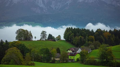 Low clouds in a valley by an Austrian village in autumn - time lapse