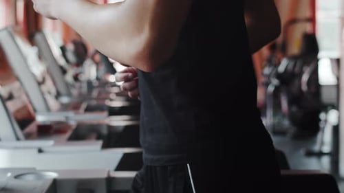 Jovem atleta masculino em roupas esportivas correndo vigorosamente em uma esteira em uma academia coberta de perto